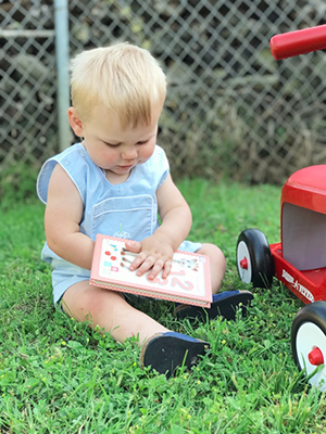 Child Reading in garden - 5 simple steps to eliminate germs from garden toys